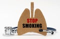 On a white surface are a stethoscope and a cardboard figure of a lung with the inscription - STOP SMOKING Royalty Free Stock Photo