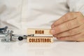 On a white surface, a stethoscope and wooden plates with the inscription - High colesterol Royalty Free Stock Photo