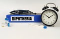 On a white surface, a thermometer, a stethoscope and a folder with the inscription - Diphtheria Royalty Free Stock Photo