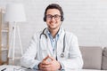 Medical conference or consultation online. Young smiling doctor in glasses with headset Royalty Free Stock Photo