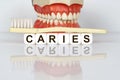 Medical, dental concept. The text is written on the cubes - CARIES. In the background is a model of the jaw, with a toothbrush on