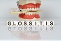 The text is written on the cubes - GLOSSITIS. In the background, a model of the jaw with a toothbrush. Prevention of dental