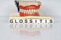 Medical, dental concept. The text is written on the cubes - GLOSSITIS. In the background is a model of the jaw, with a toothbrush