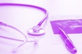 Doctor desk on lilac coloured backround with stethoscope, pen and fluoroscopic image, close up. Horizontal image