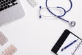 Medical desk with stethoscope, latptop, pills and blank paper on clipboard