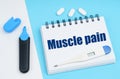 On a white-blue surface are pills, a thermometer, a marker and a notebook with the inscription - Muscle pain Royalty Free Stock Photo