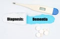 Medical diagnosis. On paper a thermometer, pills and a hole, inside which the inscription - Dementia