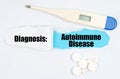 Medical diagnosis. On paper a thermometer, pills and a hole, inside which the inscription - Autoimmune Disease