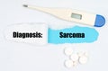 Medical diagnosis. On paper a thermometer, pills and a hole, inside which the inscription - Sarcoma