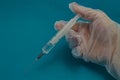 Medical disposable syringe with vaccine in hand in disposable glove close-up
