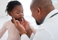 Medical doctor checking a girl throat with care in his office at a modern surgery center. Man pediatrician touching the