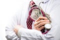 Medical doctor holding money and stethoscope in hospital setting Royalty Free Stock Photo