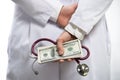 Medical doctor holding money and stethoscope in hospital setting Royalty Free Stock Photo