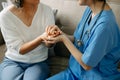 Medical doctor holing senior patient's hands and comforting her at home Royalty Free Stock Photo