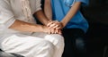 Medical doctor holing senior patient`s hands and comforting her at home Royalty Free Stock Photo