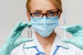 Medical doctor nurse woman wearing protective mask and gloves - holding bottle of vaccine medicine and syringe