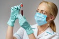 Medical doctor nurse woman wearing protective mask and gloves - holding virus blood test