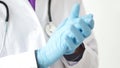 Medical doctor puting on blue latex gloves