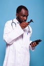 Medical doctor in white lab coat with stethoscope looking worried at otoscope Royalty Free Stock Photo