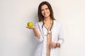 Medical doctor woman smile with stethoscope hold dreen fresh apple in hand. Isolated over white background. Royalty Free Stock Photo