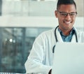 Medical doctor working on his laptop. Young doctor typing on his laptop in the hospital. Smiling doctor browsing the