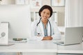 Medical doctor working on laptop and desktop computer, networking with people online and sitting at a desk at a hospital Royalty Free Stock Photo