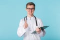 Medical doctor writing prescription over blue background showing thumbs up Royalty Free Stock Photo