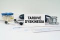 On the medical documents there is a stethoscope, syringe and a business card with the inscription - Tardive Dyskinesia