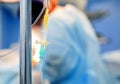 Medical drop counter on the blurry background of the group of doctors in the operating room. Closeup. Vertical. Royalty Free Stock Photo