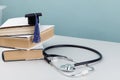 Medical education and healthcare theme. Stethoscope and graduation hat on stack of books Royalty Free Stock Photo