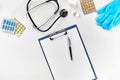 Medical equipment : pills, blue gloves, thermometer and stethoscope, white blank with a pen on white background. Top Royalty Free Stock Photo