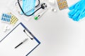 Medical equipment : pills, mask, blue gloves, thermometer and stethoscope, white blank with a pen on white background Royalty Free Stock Photo