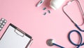 Medical equipment on pink background. Top view doctors table desk with medical clipboard, pen, pills, thermometer, stethoscope.