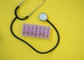 Medical stethoscope and blood pressure meter with container for pills for each day of the week, yellow background, healthcare Royalty Free Stock Photo