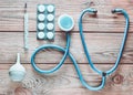 Medical equipment of the therapist on a wooden table: stethoscope, enema, thermometer, tablets, bandage. Top view.