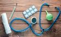 Medical equipment of the therapist on a wooden table: stethoscope, enema, thermometer, tablets, bandage. Top view.