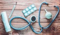 Medical equipment of the therapist on a wooden table: stethoscope, enema, thermometer, tablets, bandage. Top view.