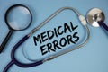 Medical Errors text with Stethoscope and magnifying glass on blue background Royalty Free Stock Photo