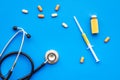 Medical examination and treatment concept. Stethoscope, syringe, pills on blue background top view Royalty Free Stock Photo