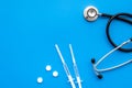 Medical examination and treatment concept. Stethoscope, syringe, pills on blue background top view copy space Royalty Free Stock Photo