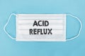 Medical face mask with ACID REFLUX text on blue background Royalty Free Stock Photo