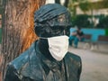 Medical face mask attached to the face of a statue on the street