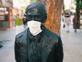 Medical face mask attached to the face of a statue on the street