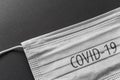 Medical face mask with COVID-19 inscription, protection against coronavirus on black background Royalty Free Stock Photo