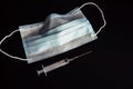 Medical face mask, disposable syringe isolated on black background, close-up. Medical supplies with space for text. Epidemic