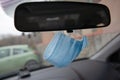 Medical face mask hanging on rear view mirror inside the car. for protect himself from bacteria and virus while driving a car Royalty Free Stock Photo