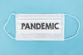 Medical face mask with pandemic text on blue background Royalty Free Stock Photo