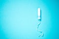 Medical female tampon on a blue background with copy space. Hygienic white tampon for women. Cotton swab. Menstruation, means of