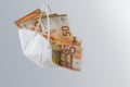 Medical ffp2 face mask against covid-19 virus filled with euro banknotes, concept for enrichment by corruption or rising costs of