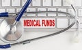 MEDICAL FUNDS word with Stethoscope on keyboard on grey background Royalty Free Stock Photo